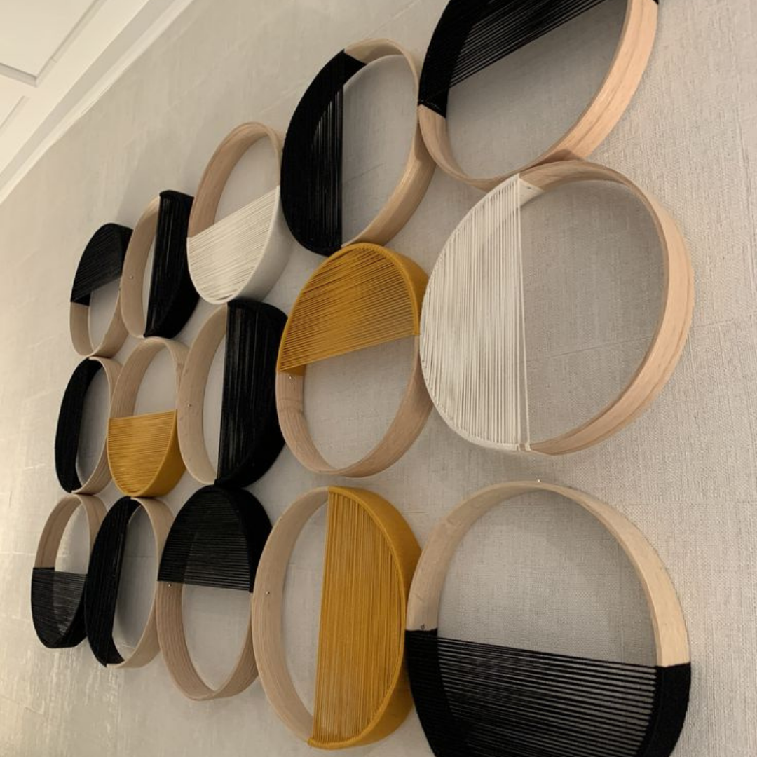 Close-up of a textured white 3D wall art featuring sculpted letters arranged in an abstract pattern on a square panel.